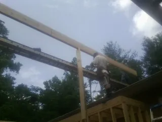 Carpenter setting a ridge beam over a new addition frame — Ice Dam Removal by Roofing Brothers in Marcy