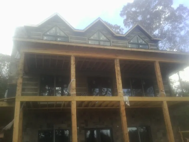 Dormers and porch framing on a large log home under construction — Roof Coating work by our crew in Marcy