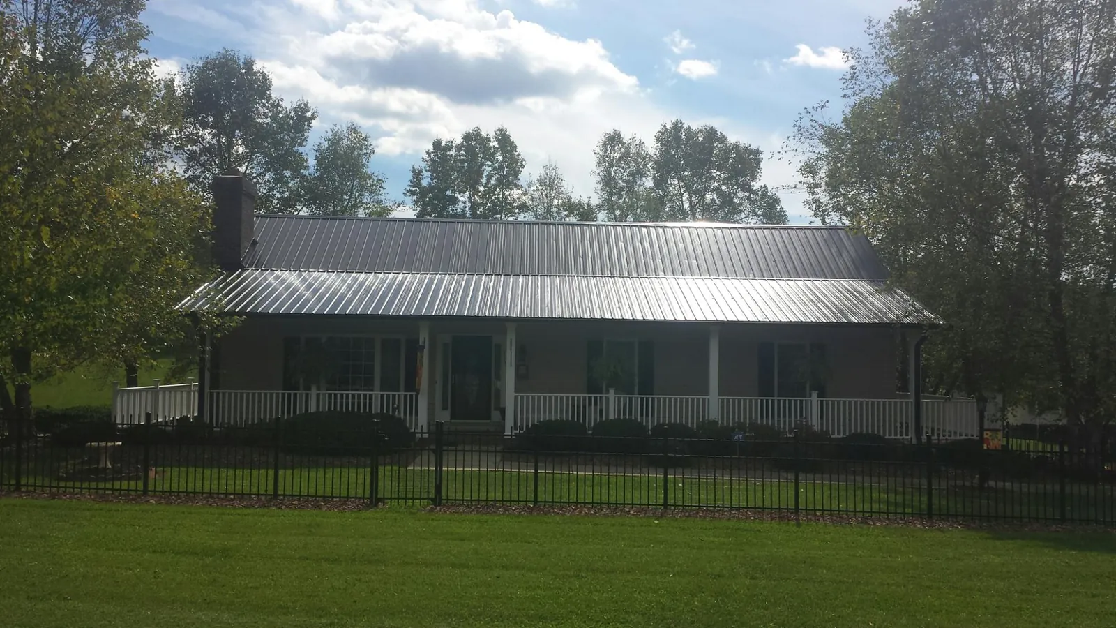 Gray metal roof on a brick ranch with a full width front porch — Gutter Guard Installation work by our crew in Marcy