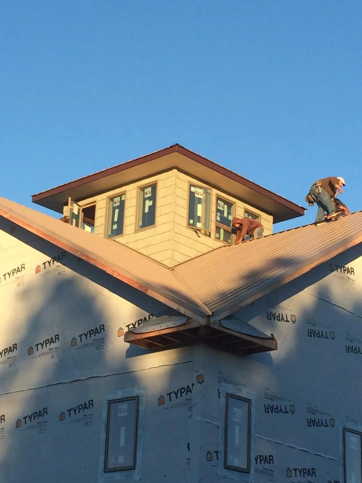 Roofers working around a rooftop cupola on a new metal roof at sunset — Roof Waterproofing in Marcy by Roofing Brothers